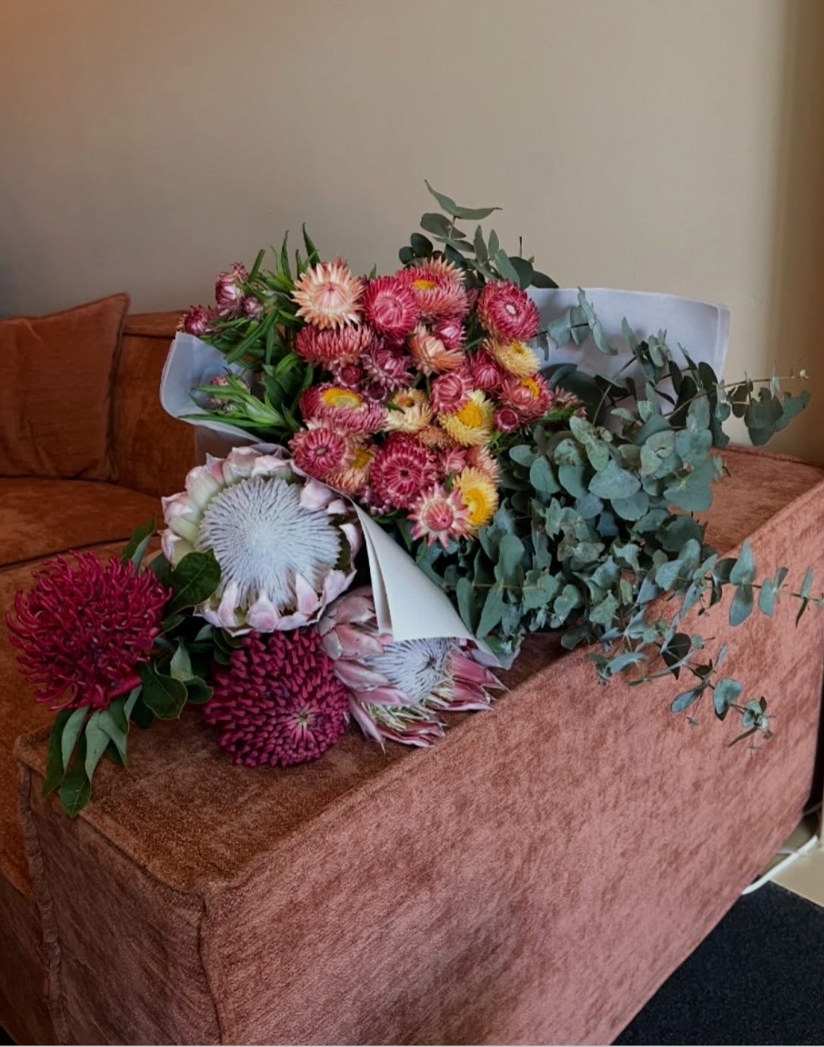 Native floral arrangement on terracotta velvet lounge at Aviano Remedial